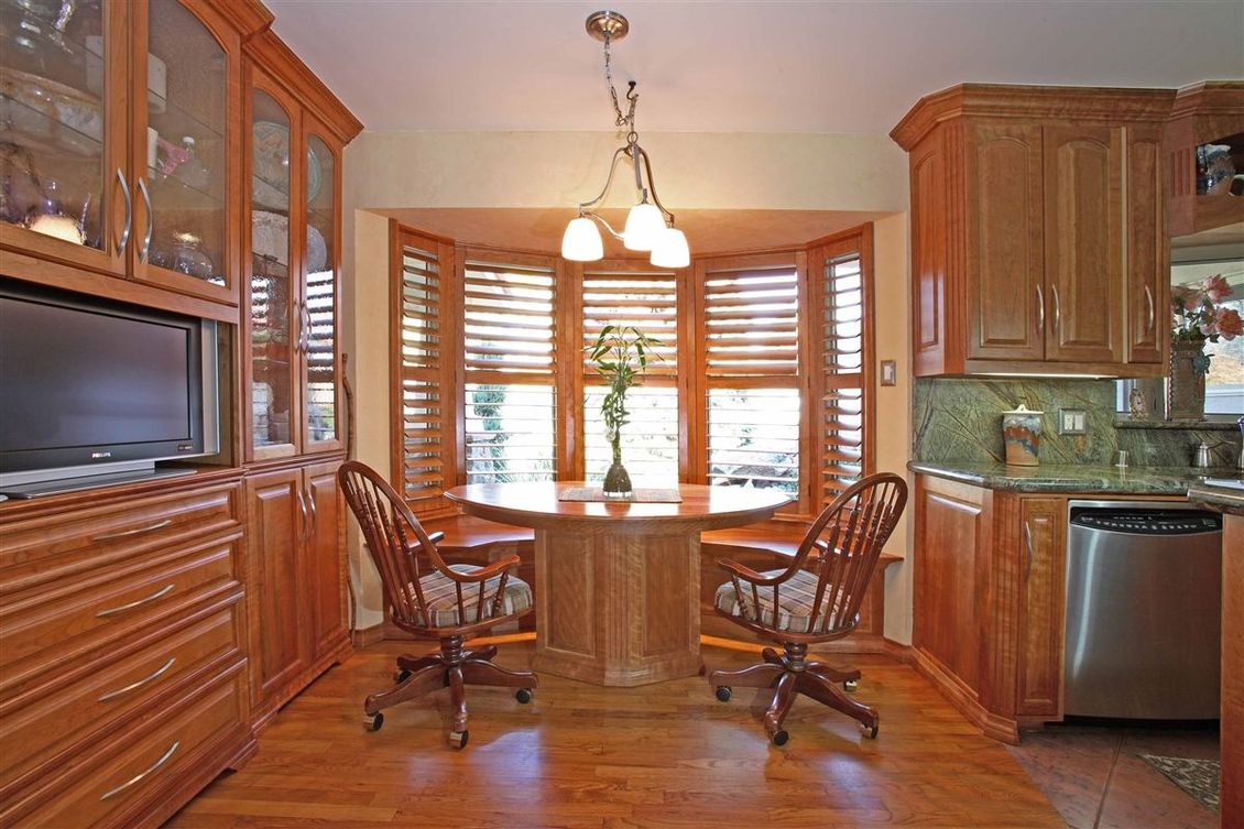 A kitchen with a table and chairs in front of a bay window.