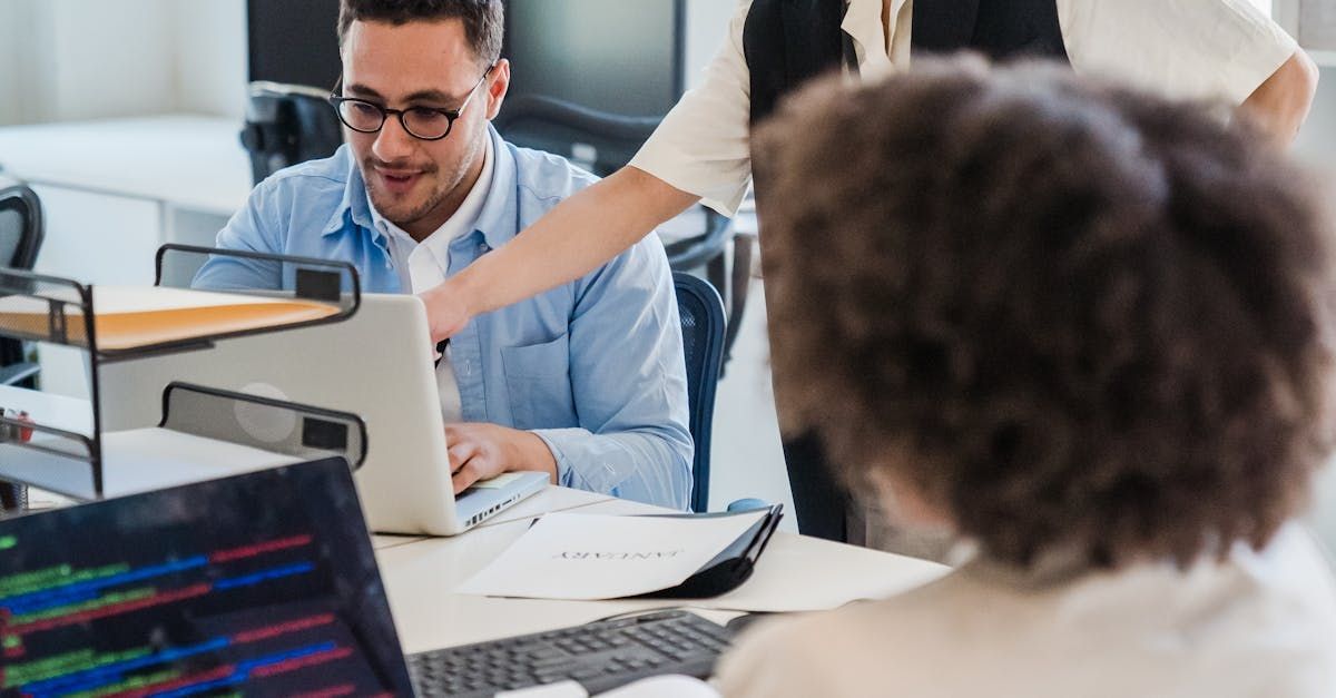 A group of people are working on a laptop computer in an office.