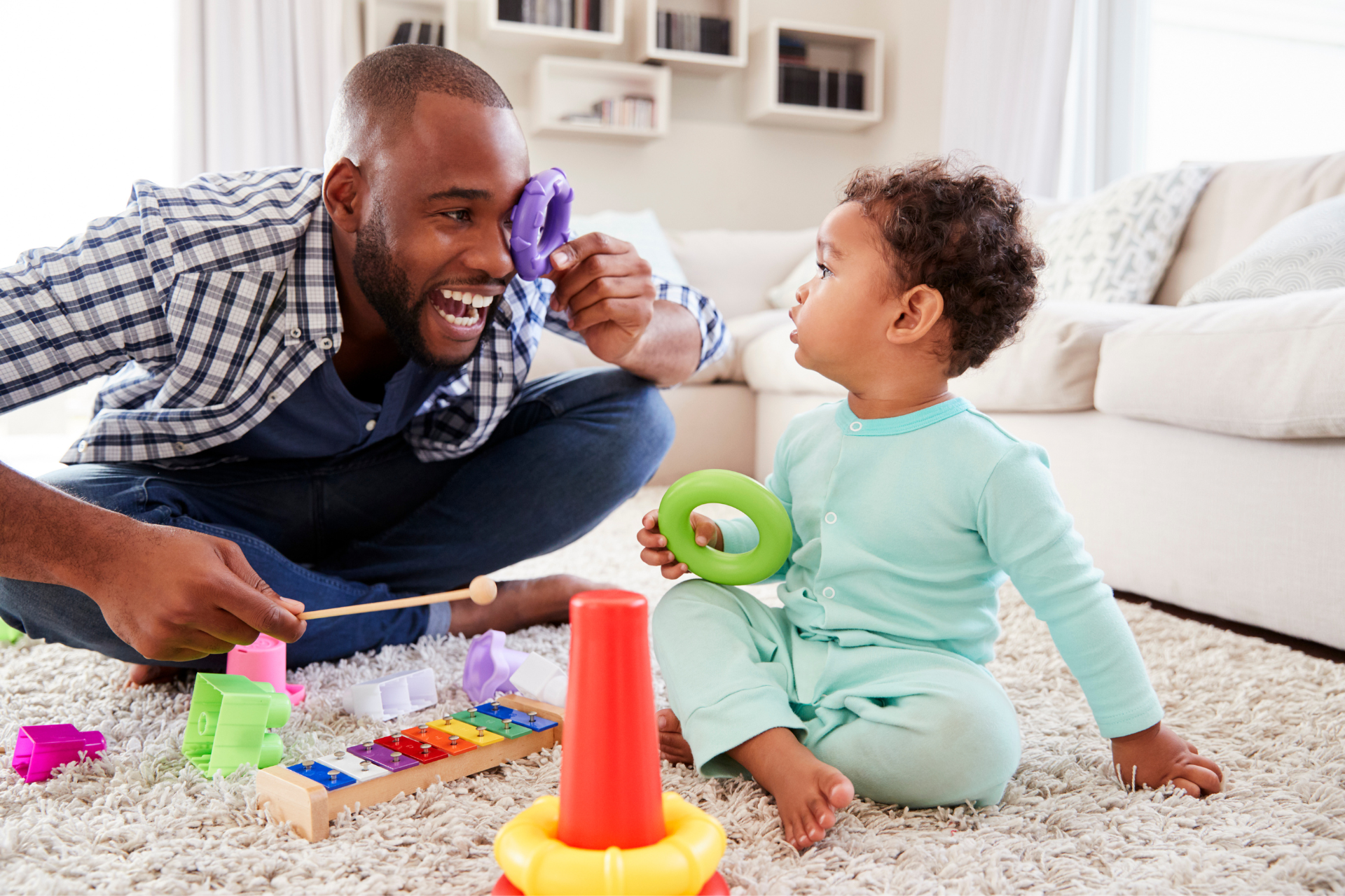 A man and a baby are playing with toys on the floor.