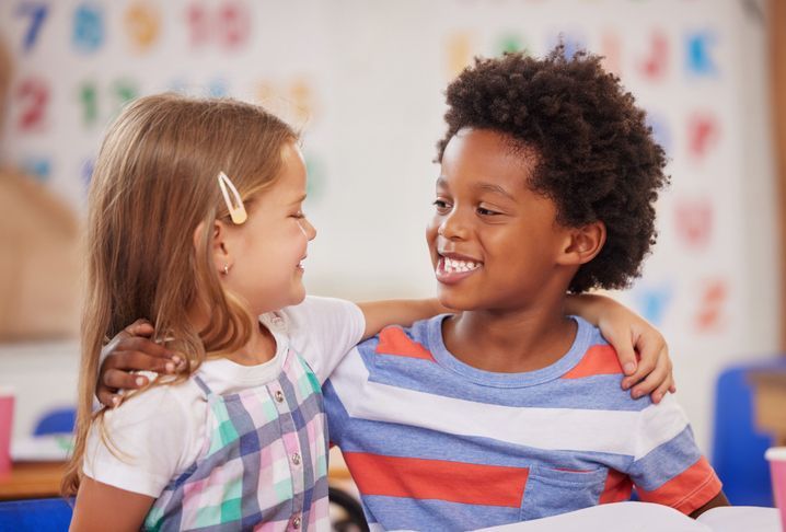 A boy and a girl are hugging each other in a classroom.