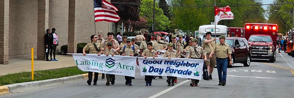 A group of people are marching down a street in a parade holding a banner.