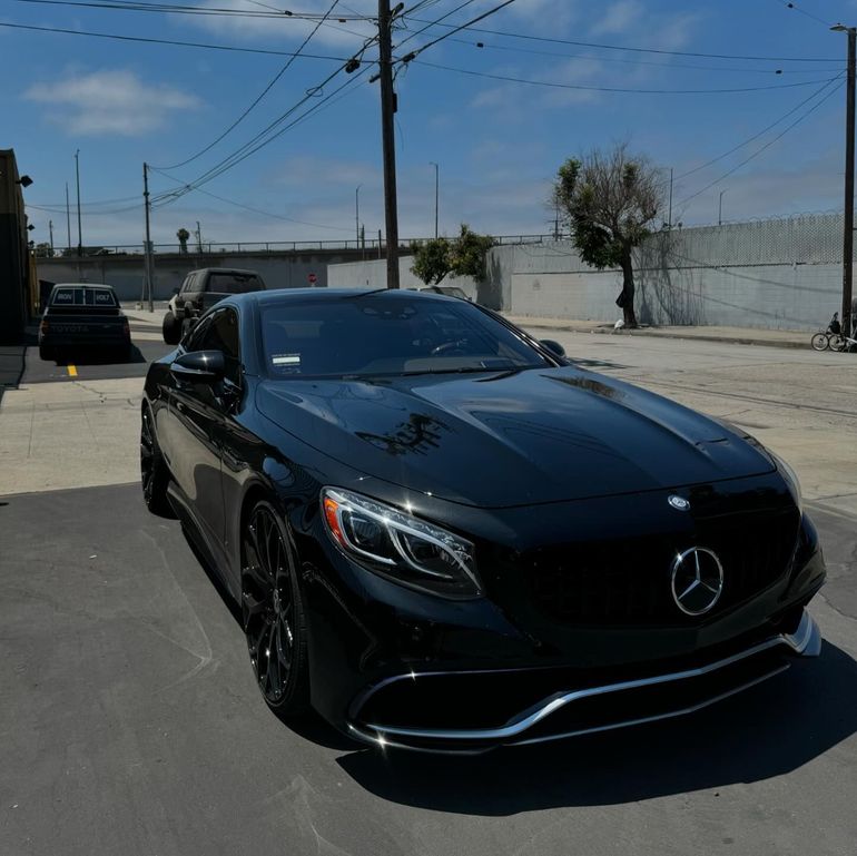 A black Mercedes-Benz coupe with a glossy finish, photographed in an outdoor setting near XWRAPS in Los Angeles