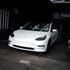 A white Tesla Model 3 is parked in a garage after PPF installation