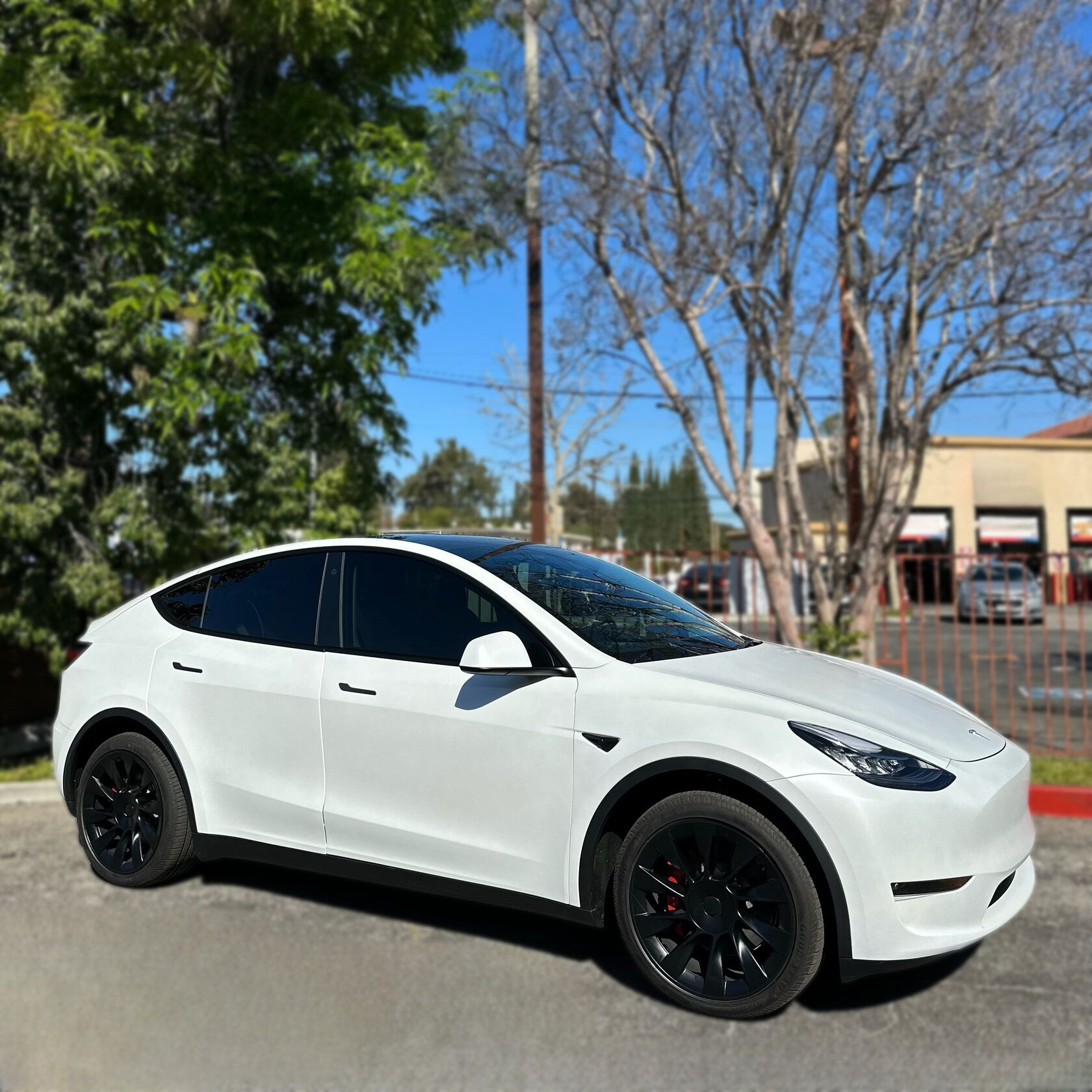 Tesla Model Y with premium ceramic coating wrap by XWRAPS Los Angeles - gleaming white finish, tinted windows, and black alloy wheels showcasing superior paint protection