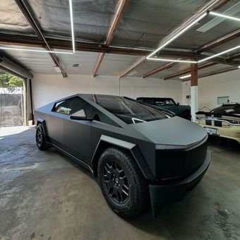 A close up of a tesla model x wrapped in matte black