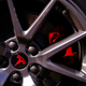 A close up of a tesla wheel with a red logo on it