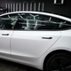 A white tesla model 3 is parked in a garage