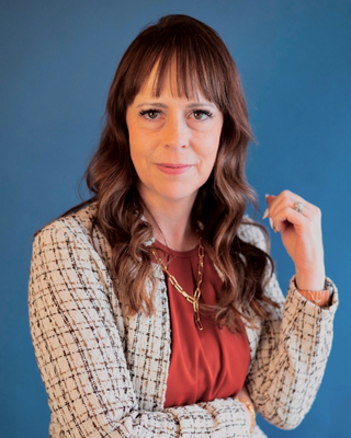 Agency founder Ashleigh George is standing in front of a blue wall.