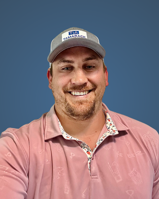 Agent Brandon is wearing a baseball hat and a pink shirt and smiling for the camera.