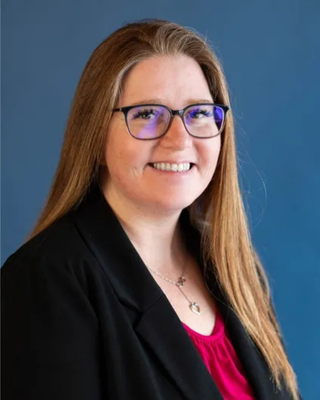 Agent Lisa is wearing glasses and a black jacket and smiling for the camera.