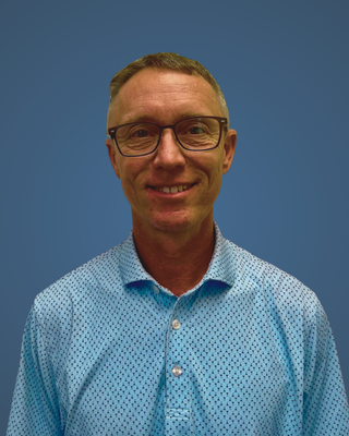 Agent Mike is wearing a blue shirt and smiling for the camera.