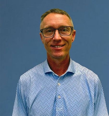 Agent Mike is wearing a blue shirt and smiling for the camera.