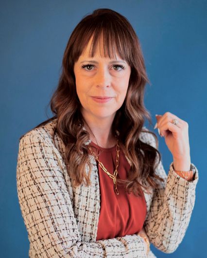 Agency founder Ashleigh George is standing in front of a blue wall.