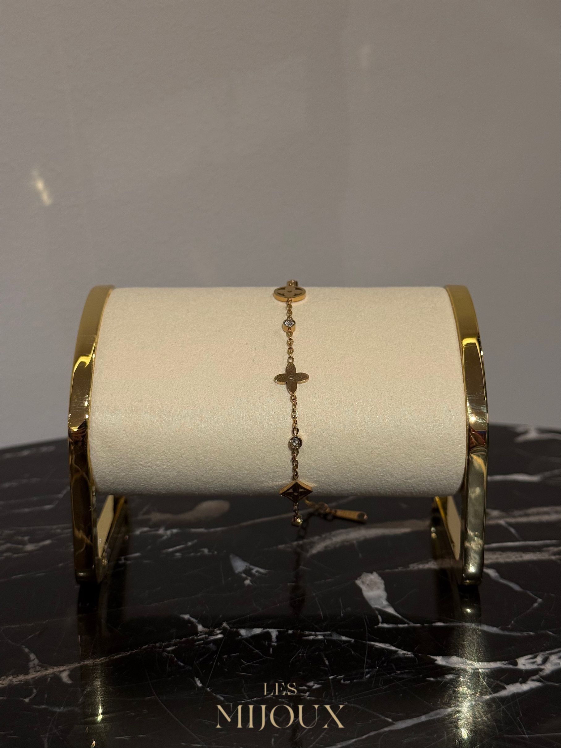 Een gouden armband met klavervormige bedeltjes.