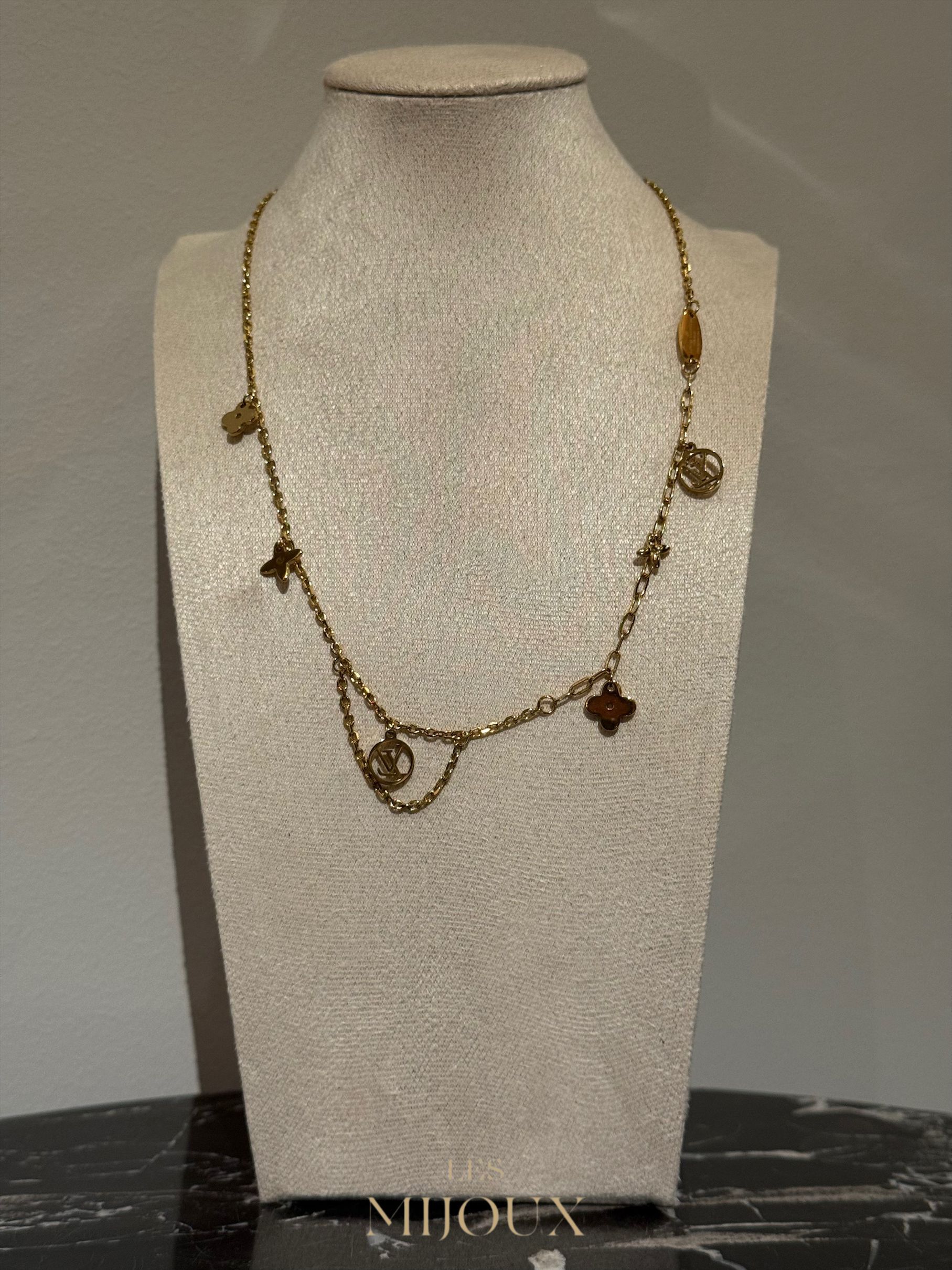 Gouden halsketting met bedeltjes op een paspop.