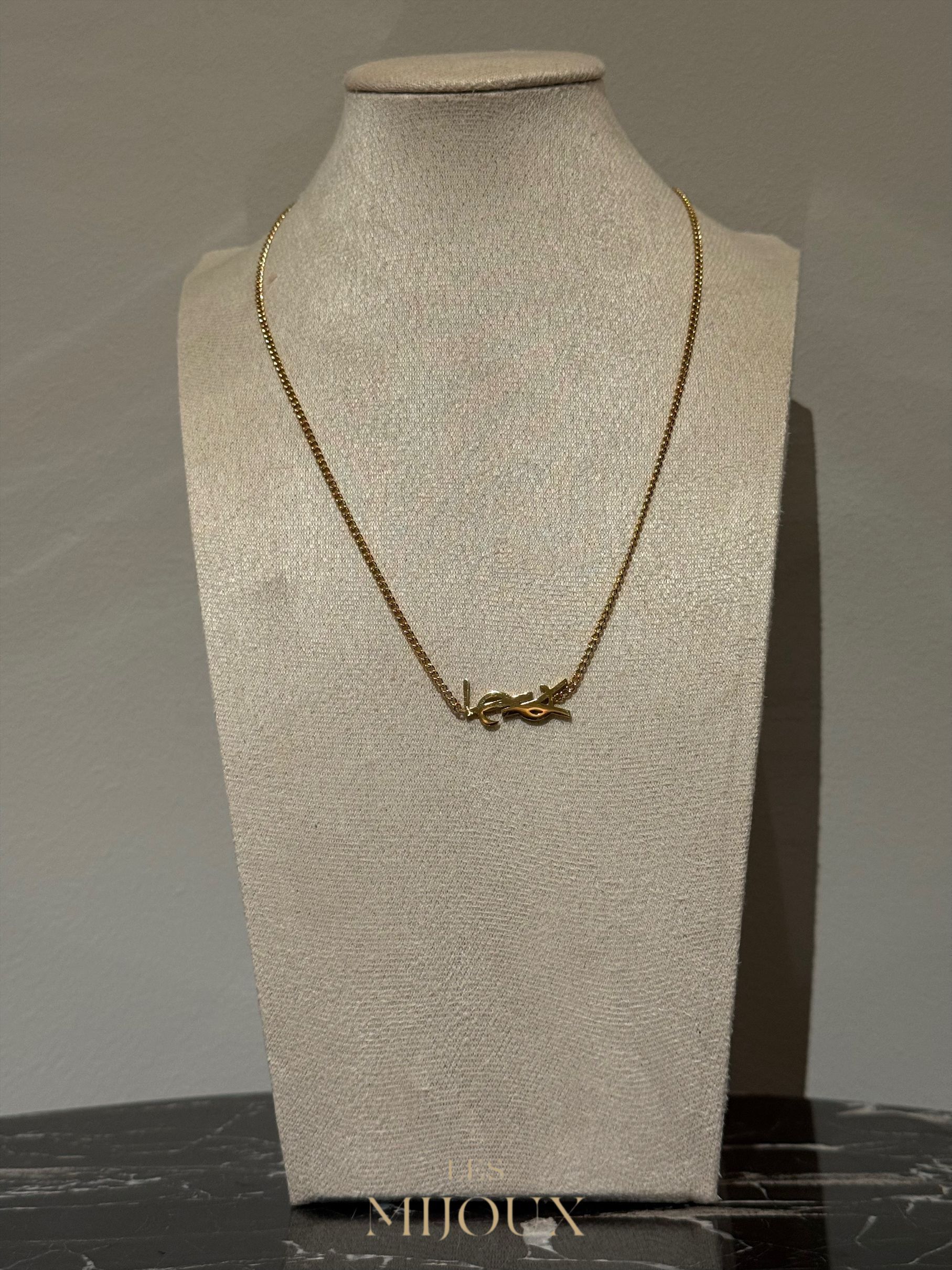 Gouden ketting op een beige sieradenstandaard.