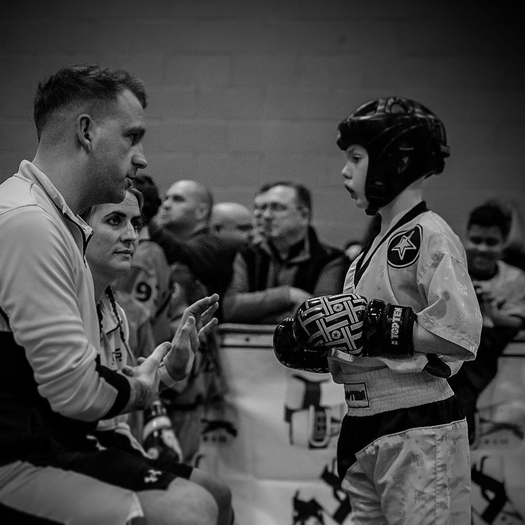 A coach gives instruction to a young martial artist in a competition. Black and white photo.