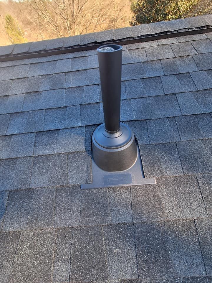 Black vent pipe on a dark gray shingle roof, outdoors.