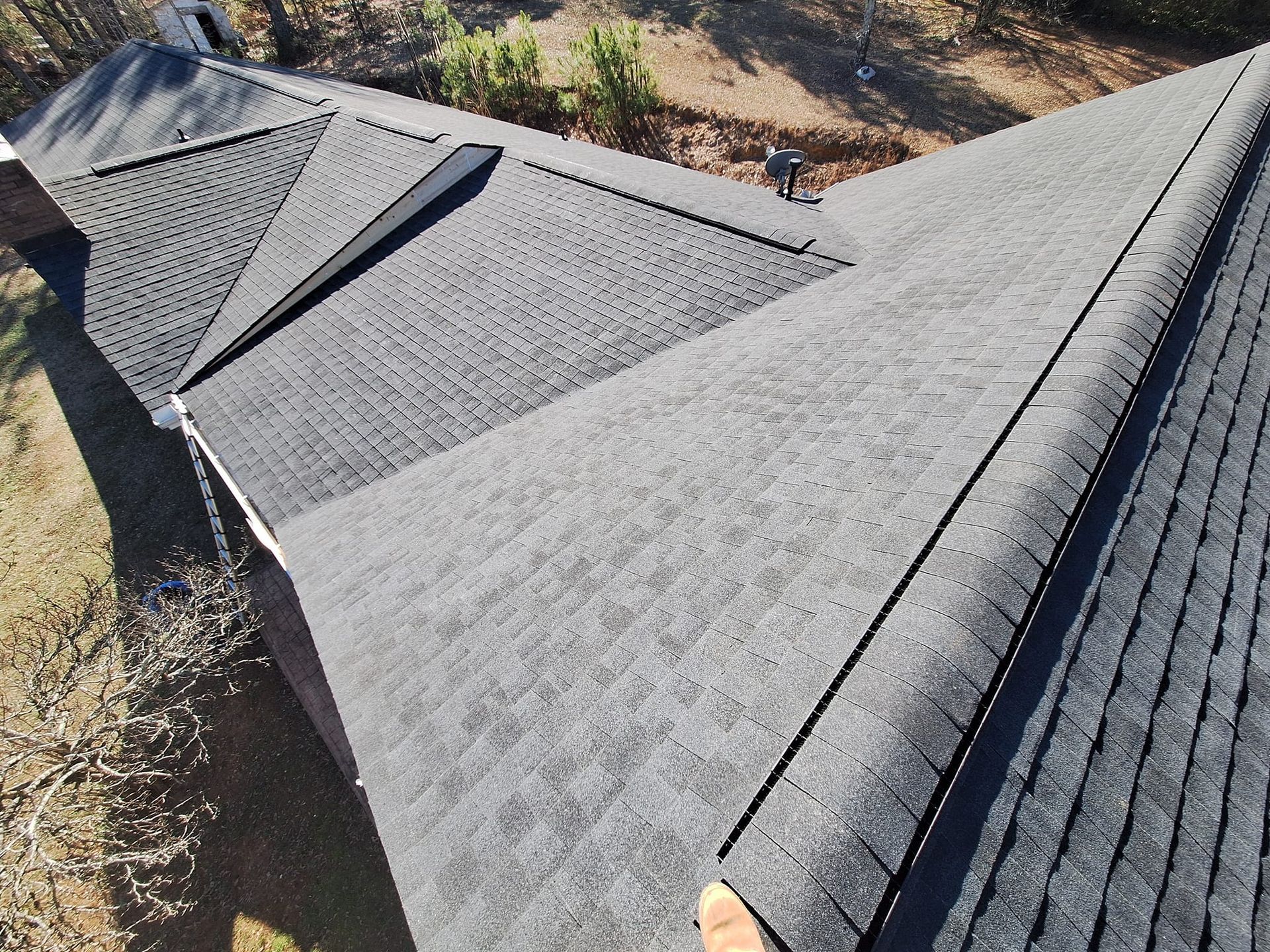 Gray shingle roof with multiple sections, a long ridgeline, and a chimney, viewed from above.