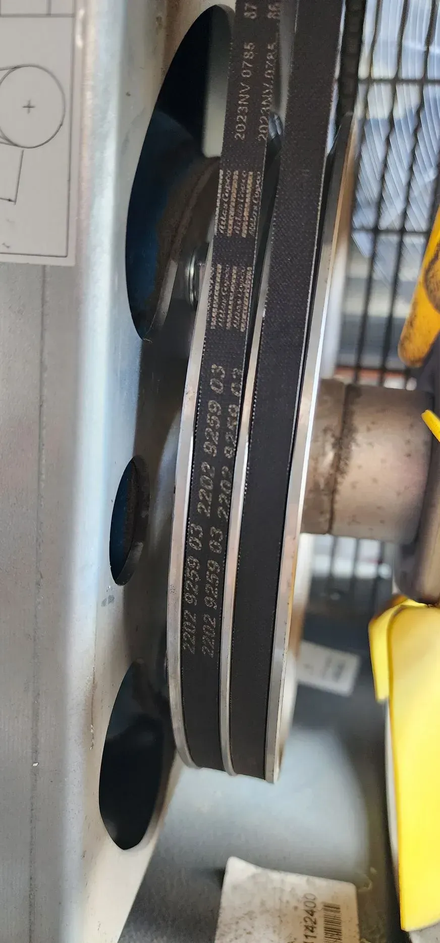 Close-up of a machine's pulleys and belt system, showing details of the belt and pulleys.