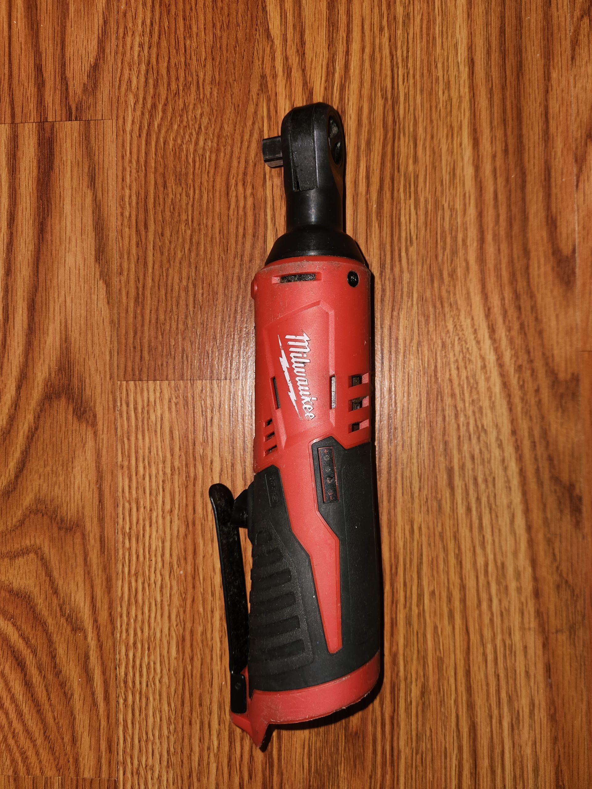 Red and black Milwaukee cordless ratchet on a wooden surface.