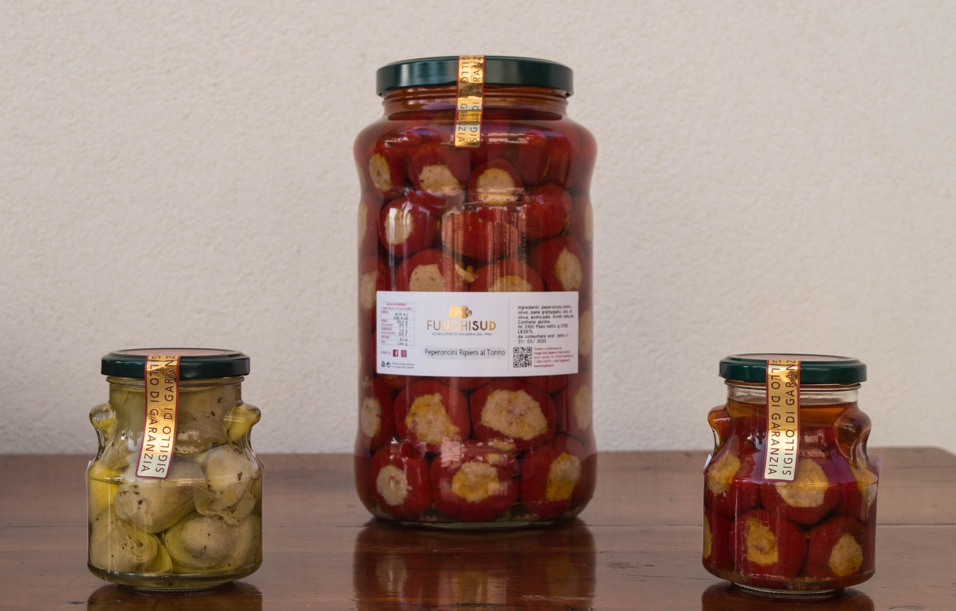 Tre barattoli di cibo sono appoggiati su un tavolo di legno.