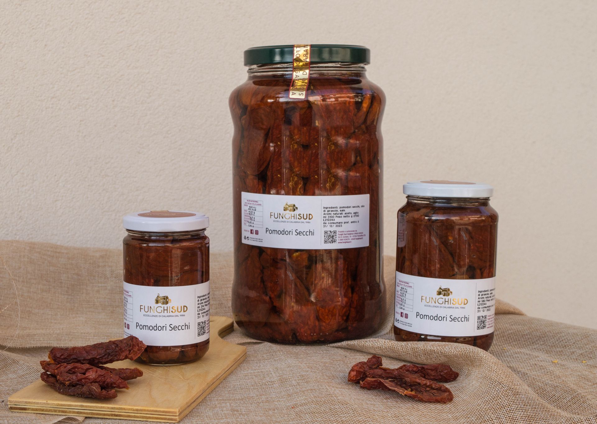 Tre barattoli di pomodori secchi sono appoggiati su un tavolo.