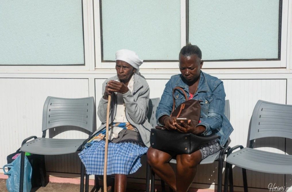 Two women are sitting in chairs in front of a building.