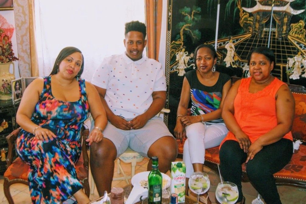 A group of people are sitting around a table with a bottle of beer on it.