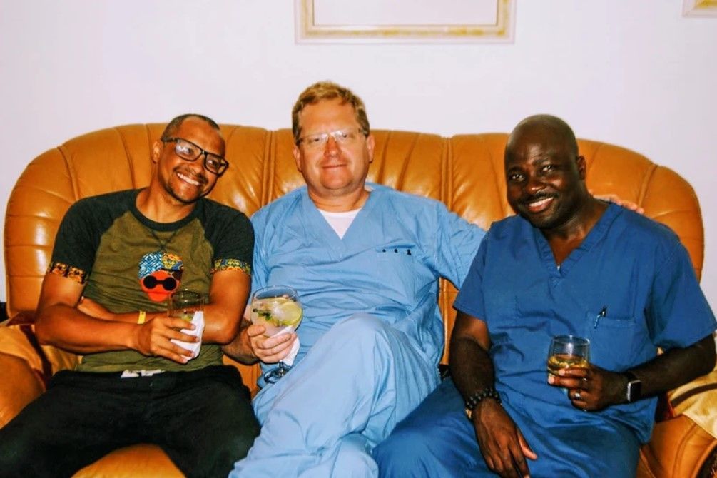 Three men in scrubs are sitting on a couch