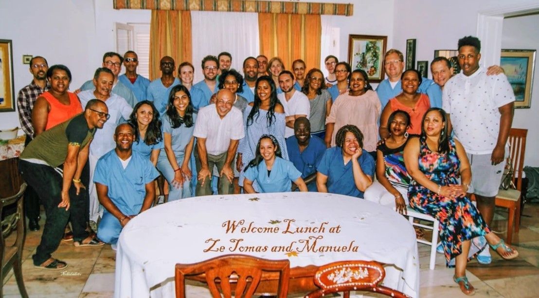 A group of people are posing for a picture in front of a table that says welcome lunch on it