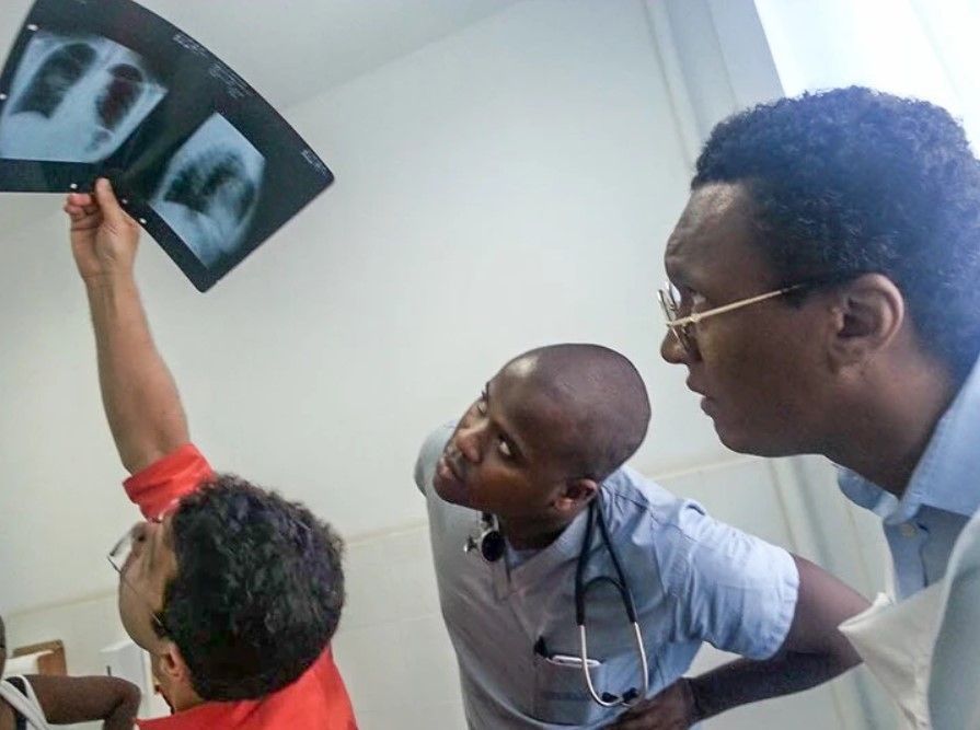 Three men are looking at an x-ray of a person 's lungs