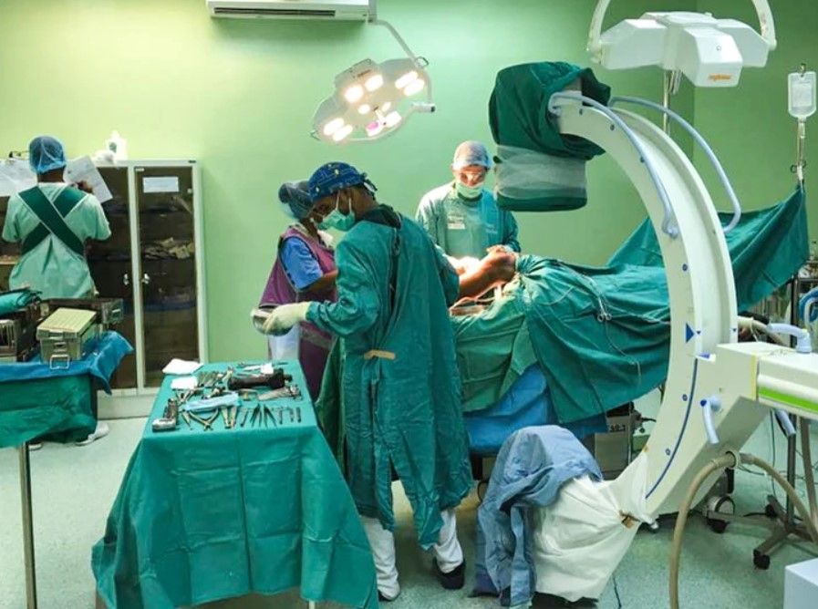 A group of surgeons are performing surgery on a patient in an operating room