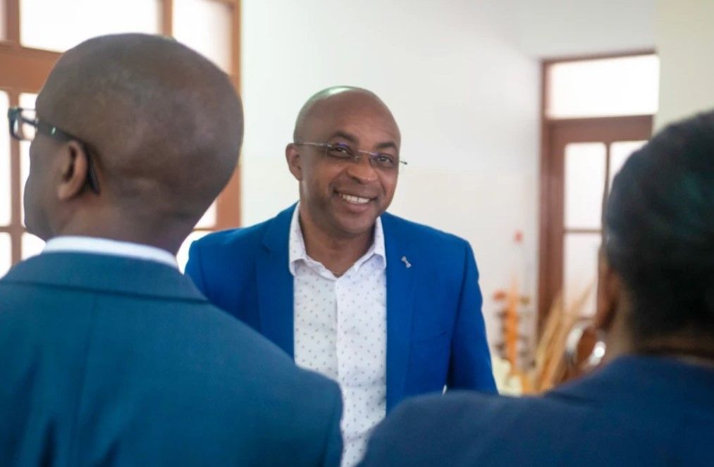 A man in a blue suit is talking to two women in a room.