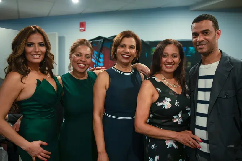 A group of women and a man are posing for a picture together.