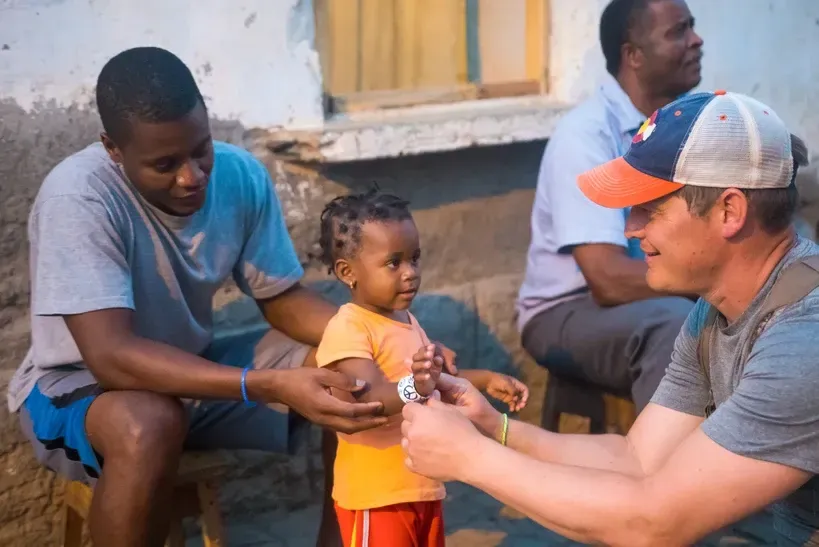 A man is holding a little girl while another man looks on.