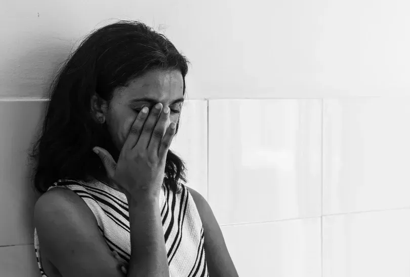 A woman is crying and covering her face with her hand.