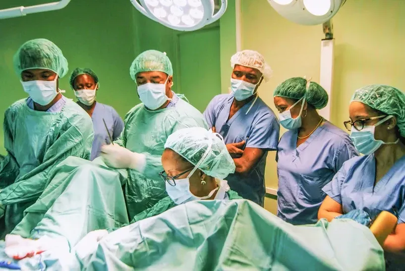 A group of surgeons are operating on a patient in an operating room.