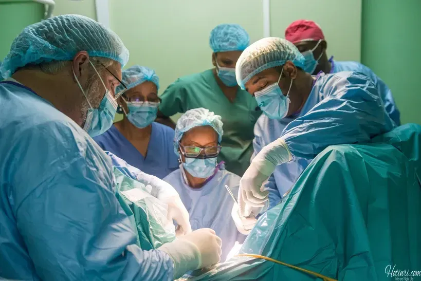 A group of surgeons are operating on a patient in an operating room.