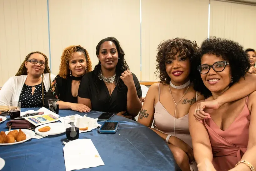 A group of women are sitting at a table posing for a picture.