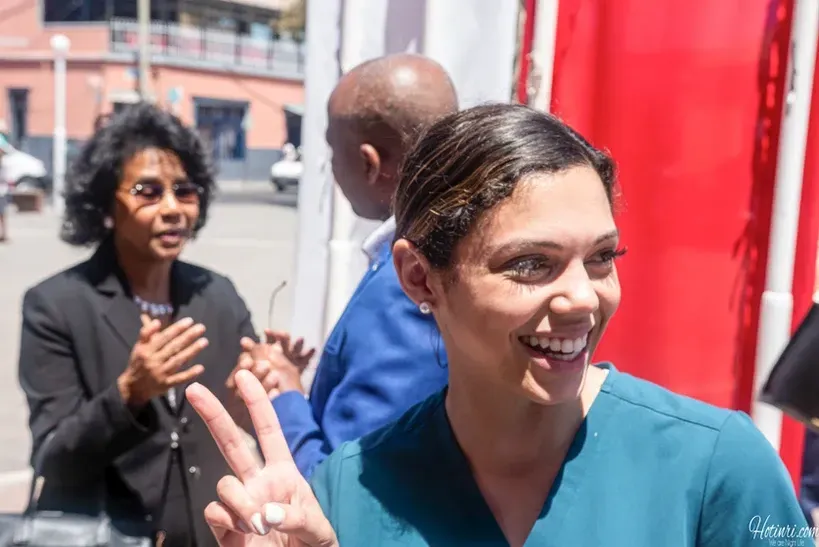 A woman in a scrub top is giving a peace sign.