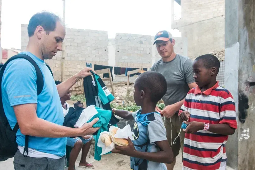 A man is giving a sandwich to a young boy.
