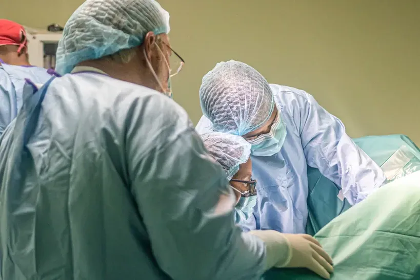 A group of surgeons are operating on a patient in an operating room.