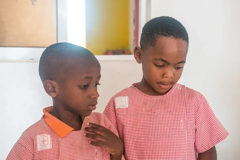 Two young boys are standing next to each other in a room.