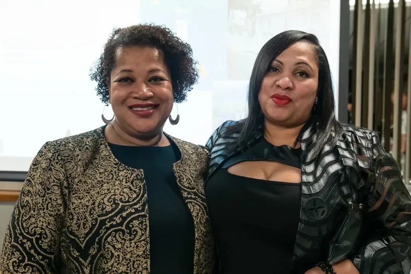 Two women are posing for a picture together and smiling for the camera.