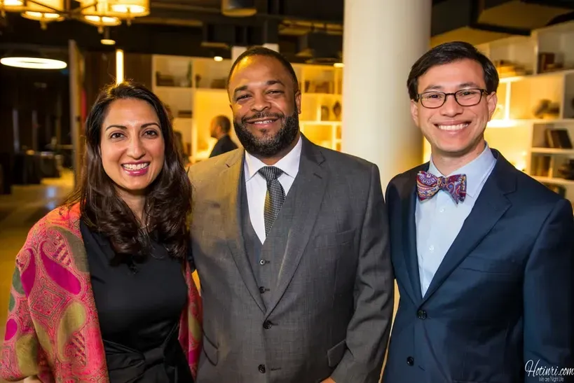 Three people in suits and bow ties are posing for a picture.