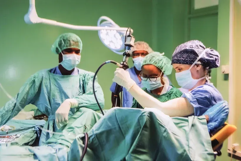 A group of surgeons are operating on a patient in an operating room.