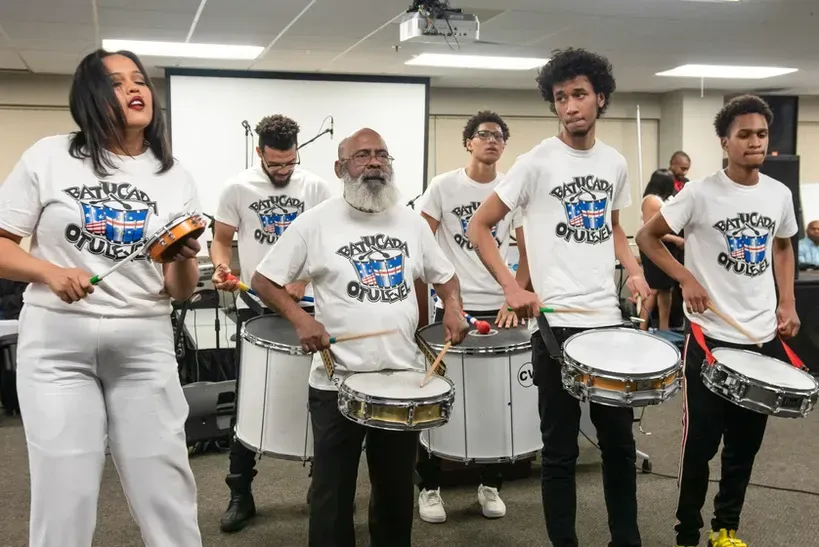 A group of people are playing drums in a room.