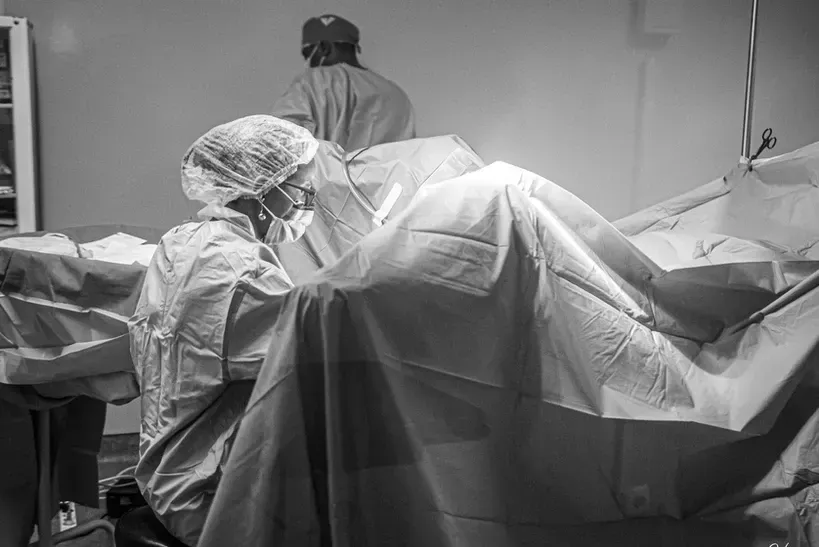 A black and white photo of a surgeon in an operating room.