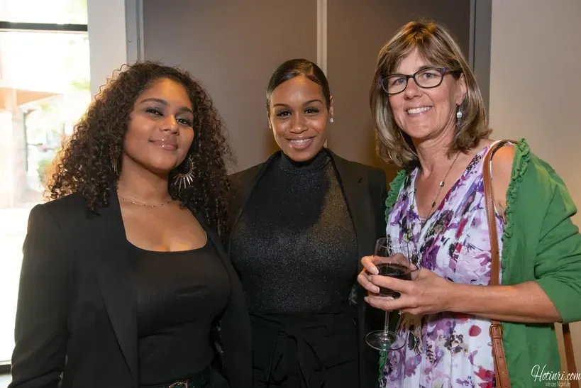 Three women are posing for a picture together while holding wine glasses.